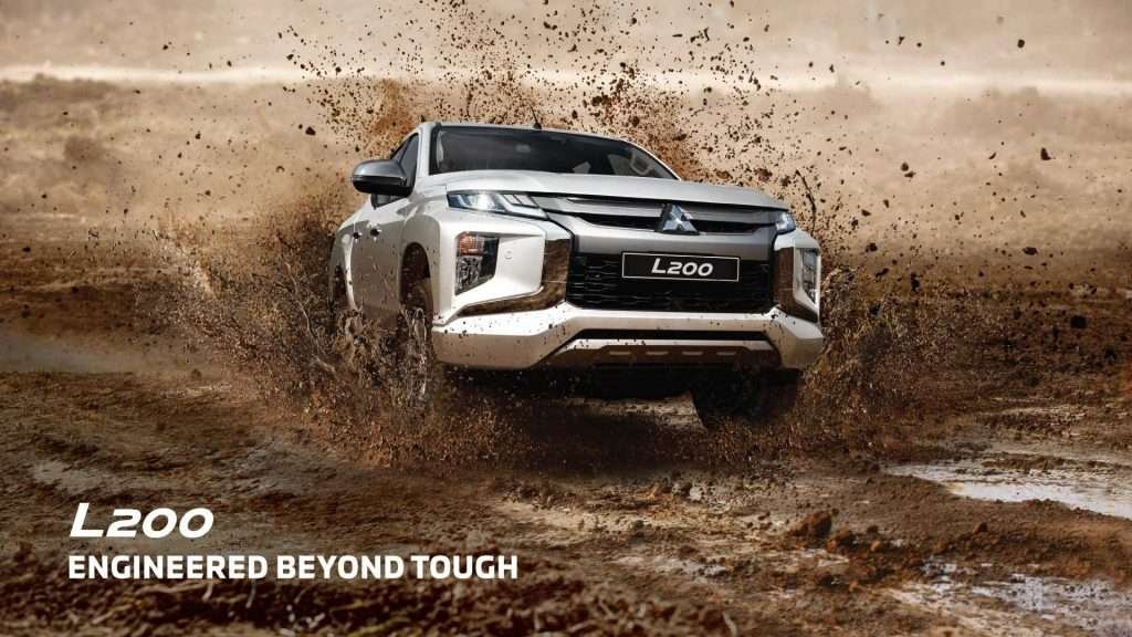 White Mitsubishi L200 driving through mud